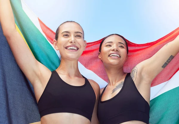 Women, South Africa and flag, winner in sport event or running in global competition. Smile, happy and girl show team diversity in celebration after win at sports tournament or international race.