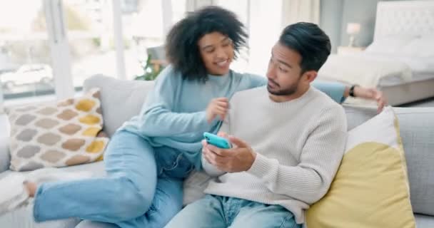 ソーシャルメディア 彼らの家のリビングルームでソファに抱きつくカップルとの愛 彼らの家で一緒に抱擁幸せな若い男と女性とモバイル 技術と愛情 — ストック動画