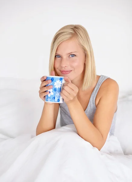 暖かいコーヒーカップで目を覚ます ベッドに座っている間に魅力的な若い女性がコーヒーを飲む — ストック写真