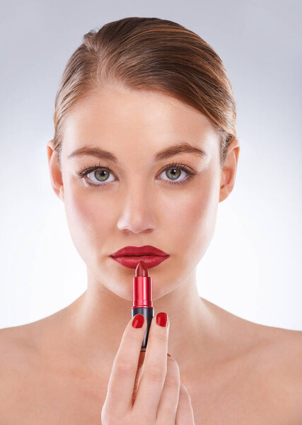 Red is the color of desire. Portrait of an attractive young woman wearing bright red lipstick and nail polish