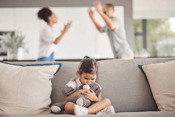 Depression, stress or child trauma for girl with teddy bear on living room sofa and listening to fight, scream or shouting parents. Burnout, anxiety or mental health kid with divorce father or mother.