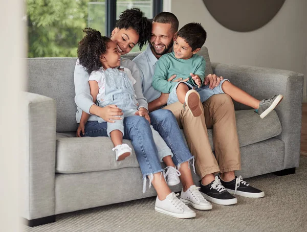 Happy family relax on home sofa in Brazil, parents smile at children on casual day together. Lounge in living room, young african kids bond with black mother and funny father make dad jokes on couch.