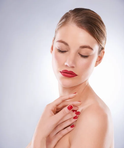 Highlighting her most beautiful features. Portrait of an attractive young woman wearing bright red lipstick and nail polish