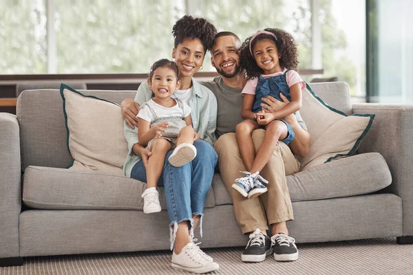 Happy interracial family on sofa portrait of children and parents or mother and father for love, care and support. An immigrant Mexico dad and mom with Asian and african kid together on lounge couch.