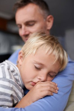 Babaların omzunda uyumak. Yetişkin bir baba işten eve geliyor ve yorgun küçük oğluna sarılıyor.
