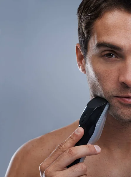 Modern day metrosexual. A young man shaving with an electric razor