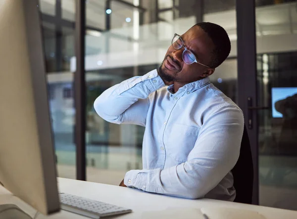 Burnout, stress and neck pain by businessman working on a computer late in office, injury and discomfort. Corporate employee suffering from hurt and tender spinal injury while working overtime.