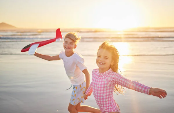 日没の地平線と海の波の健康 健康的な開発のために一緒にビーチで飛行機のおもちゃで走っている子供たち 屋外の夏休みの肖像画のための楽しさと遊びを持っている子供 — ストック写真