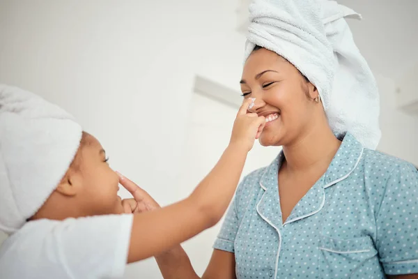 Skincare, beauty and mother and child with sunscreen, face cream or lotion in bathroom towel for love or happiness. Funny nose touch on playful mom, daughter or black family doing self care together.
