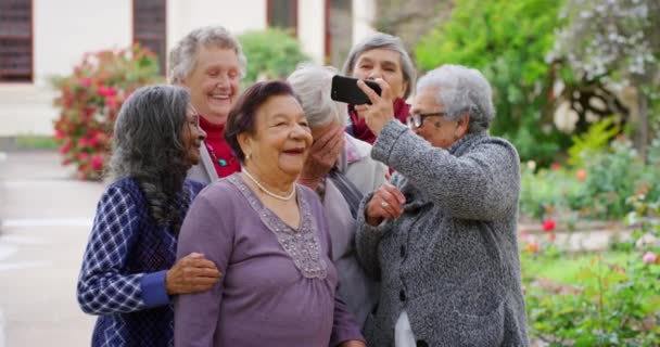 老年妇女和户外自拍者一起在花园里用智能手机参加快乐的社交活动 在手机上拍下了人们在疗养院里欢欢喜喜地重逢的照片 — 图库视频影像