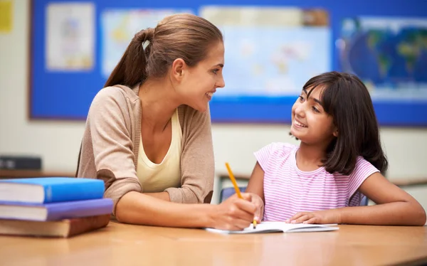 T is for teacher and also for thank you. a teacher helping her student with her work in the classroom