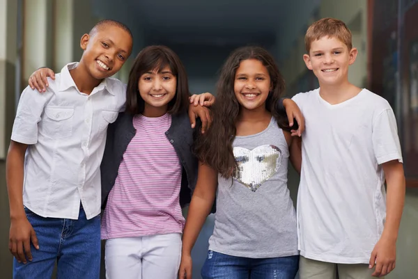 School friends. Four friends standing arm-in-arm in the corridor of their school