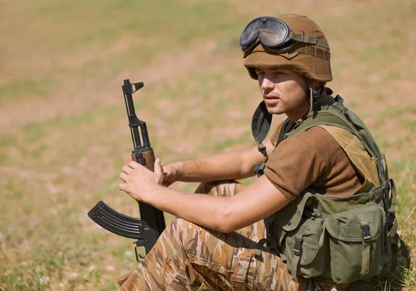 等着敌人 一个年轻的士兵坐在外面的草地上 — 图库照片
