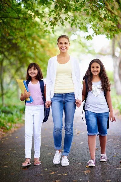 Shes a caring educator. A teacher walking with her two students to school