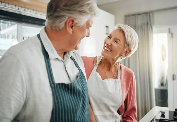 Couple, cooking and love with a senior man and woman in the kitchen to prepare food or a meal at home. Retirement, happy and smile with an elderly male and female pensioner together in their house.