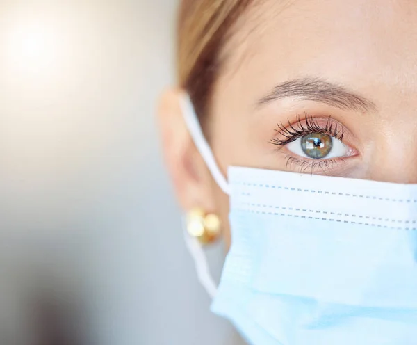 Covid health, face mask and humanity with closeup of eye of young woman wearing protection, precaution and safety. Portrait of a female and healthcare against coronavirus, flu and cold in a pandemic.