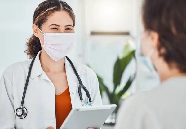 Covid, tablet and doctor consulting patient, woman or girl about test results, medicine or health. Healthcare worker, hospital employee or medical expert with safety mask talking to clinic client.