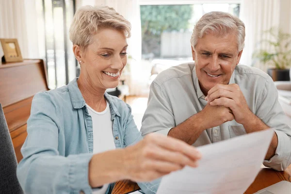 Happy couple, reading and paperwork or document for bill, mortgage or retirement plan or payout while sitting at home. Mature man and woman busy with tax compliance or finance form for pensioners.