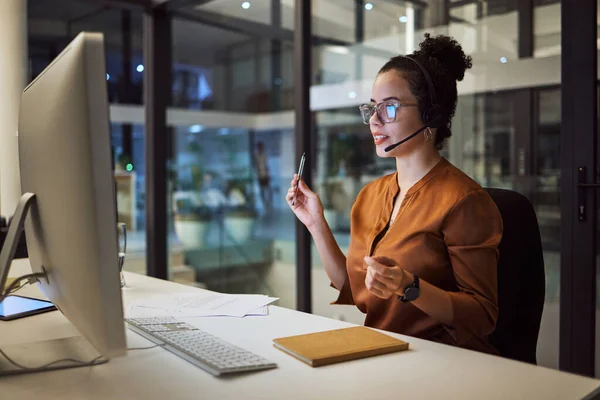 Call center, customer support and insurance agent consulting at night in a office at a contact help desk. Sales, telemarketing and employee working hard in helping, talking and listening via headset.