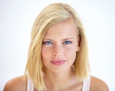 Intensity in her eyes. Head and shoulders portrait of a pretty young blonde standing in a studio clipart
