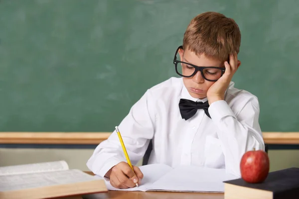 別のテストじゃない 本に絶望的に書かれているクラスで座っている眼鏡と蝶ネクタイを持つ若い男の子 — ストック写真