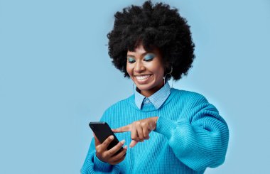 Happy, telefon ve siyahi kadın bir internet sitesinde maket alanı olan bir stüdyoda blog okuyor. Mutluluk, gülümseme ve sosyal medyada iletişim kuran Afrikalı kız mavi arka planlı akıllı telefon gibi.