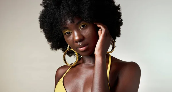 Black woman, face and makeup with skincare beauty and cosmetics against grey backdrop. Model, hand and hair, show afro, skin wellness and health in portrait against studio background in Los Angeles.