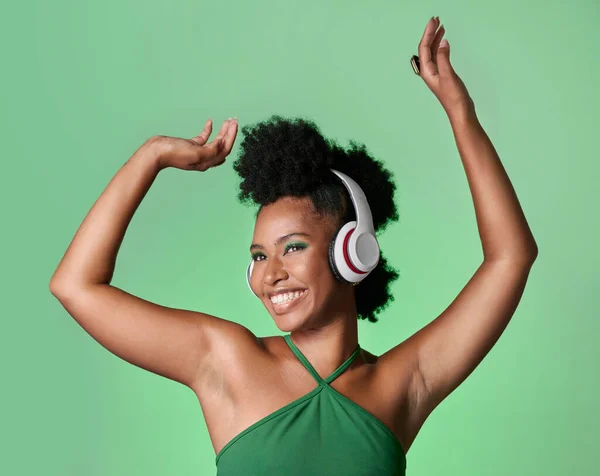 Green screen music, radio dance and black woman with smile while streaming podcast against a mockup studio background. Happy and smile African person with dancing energy from audio with headphones.