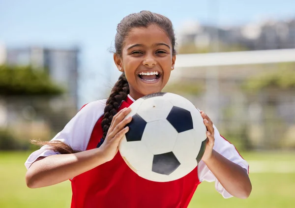 Soccer, sports and happy Indian girl athlete holding a sport ball on a school field. Portrait of fitness, football and exercise of a child smile excited about training, workout and game motivation.