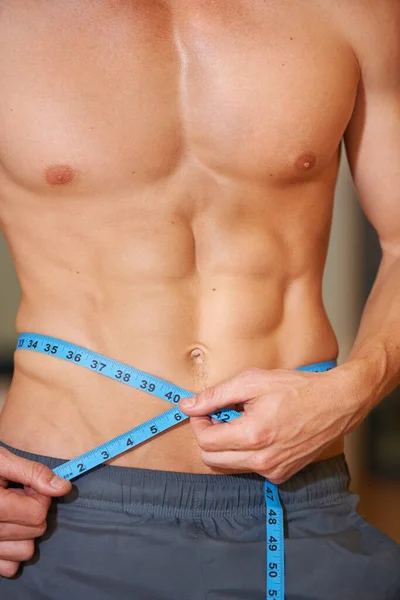测量那些腹肌肌肉男用测量带测量他的腰部和腹肌 — 图库照片