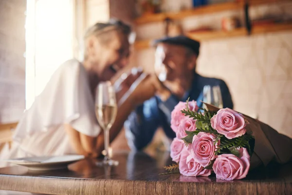 Love, celebration and of roses for couple marriage anniversary with champagne for toast. Romantic, happy and caring senior people in relationship commitment together enjoy intimate date