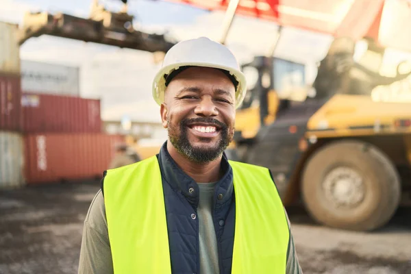 Portrait, smile and work in logistics with container at export and distribution shipyard. Black man, happy and confident has motivation working in shipping, cargo and supply chain industry at port.