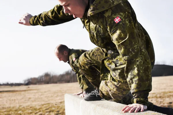 Taking the obstacle course by storm. Trainee soldiers jumping over a wall in an obstacle course