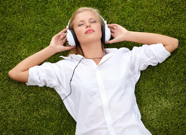 音楽に没頭している 彼女の目を閉じて音楽を聞いて草原のフィールドに横たわっている女性の高角度ショット — ストック写真