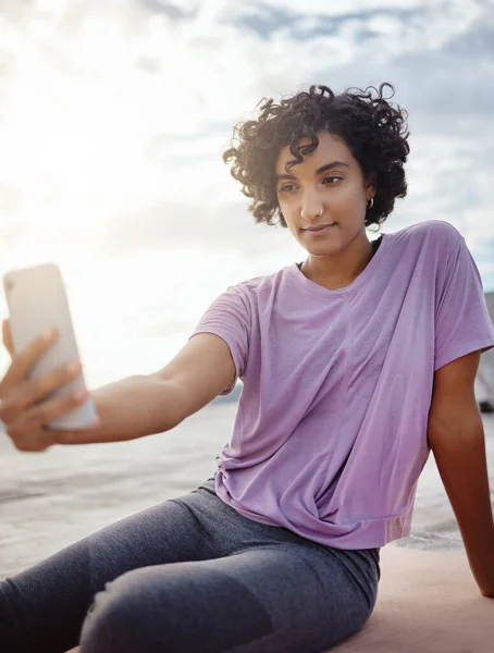 フィットネス 女性は 市内の屋外ワークアウトをしている間に電話で自撮りをします マットでヨガをしている間 スマートフォンで写真を撮るプエルトリコから若いと女の子アスリート — ストック写真