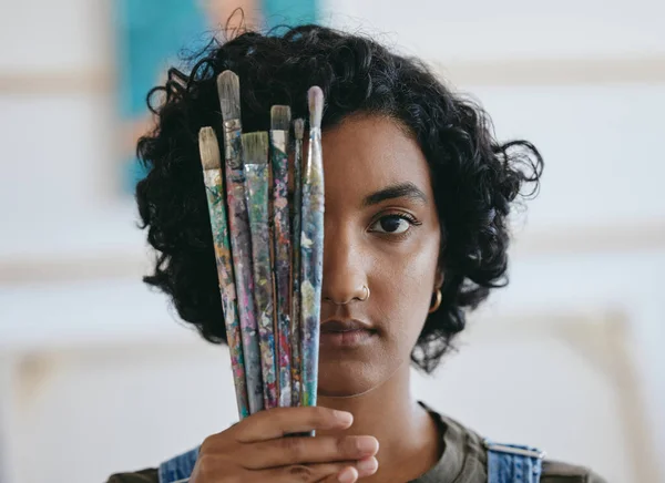 Brush, portrait and woman is a creative painter in an art gallery or workshop studio for watercolor painting. Freedom, artist and Indian girl with paintbrushes for her craft, hobby and drawing talent.