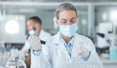 Laboratuvarda ilaç analiz tüpüyle laboratuvar maskesi ve aşı araştıran bir kadın var. Tıbbi gelişim, yenilik ve profesyonel bilim uzmanı bir laboratuarda yeni tıbbi analizler üzerinde çalışıyor..