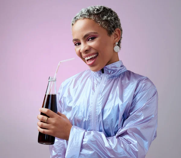 Happy, excited and portrait of a black woman with a soda in a studio with a purple background. Stylish, fashion and young african model with a smile drinking a bottle of cola beverage with a straw