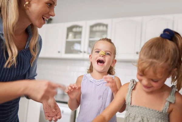 Home kitchen, children play while cooking with happy mother and funny family time learning to bake. Crazy girl child with flour dough on nose, laugh together helping mom smile and sweet kids have fun.