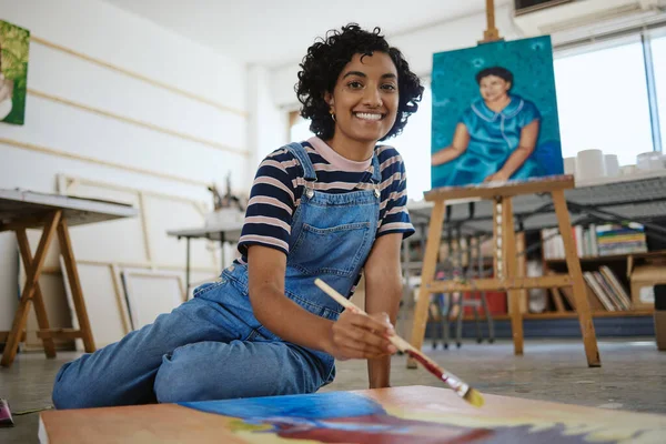 Woman, painter and art in creative workshop with happy smile for freelance in colorful arts and talent. Portrait of a freelancer female artist painting on a canvas smiling in studio for creativity.