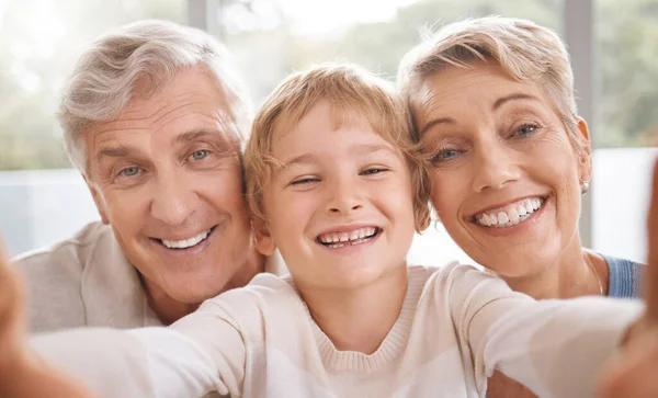 笑顔で 彼らの家で家族の絆をケアし リビングルームで祖父母 自撮りや幸せな家族の肖像画一緒に リラックスして陽気な高齢者と女性は興奮した孫との時間をお楽しみください — ストック写真