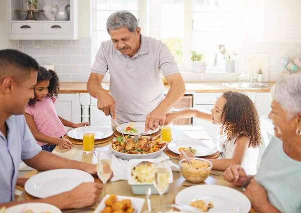 Family lunch, home celebration and grandparents hosting a dinner at kitchen table for children with turkey chicken. Girl kids, father and senior people eating food together with love in their house.