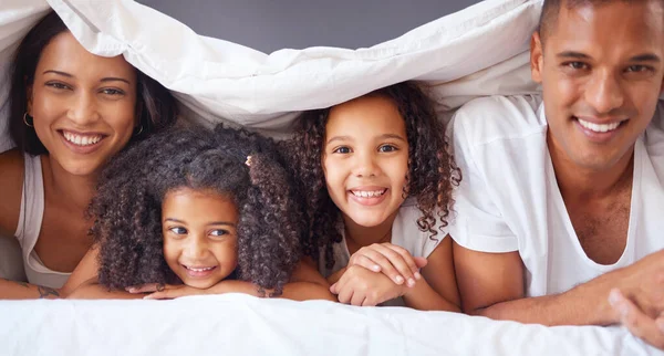 Portrait of happy black family bonding on a bed, relax and smile in a bedroom together. Love, blanket and happiness parents enjoying free time with their children, being playful and love in morning.