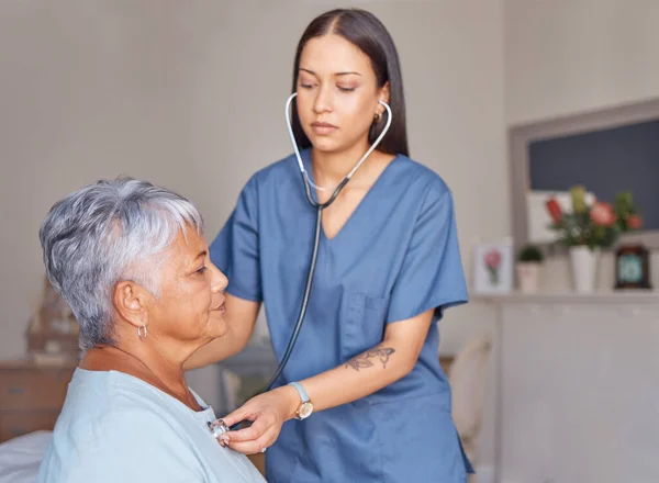 Elderly patient, nursing and nurse with a stethoscope listening to heartbeat during a health consultation. Healthcare professional, senior woman and medical checkup in her room at the retirement home.