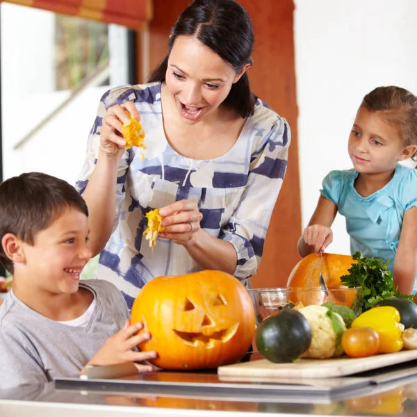 I think its ready. a mother helping her children carve pumpkins for halloween