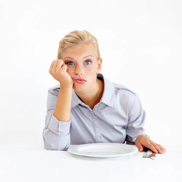 空の皿の前に座っている退屈した若い女性 — ストック写真