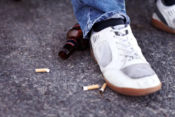 レールから降りるんだ 捨てられたタバコの吸い殻やビール瓶の横に立っている人の閉鎖ショット — ストック写真