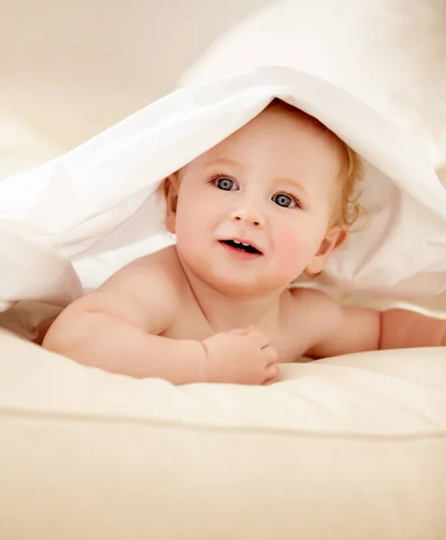 探索他的世界可爱的男婴嬉闹地躺在床单下 望着别处 — 图库照片