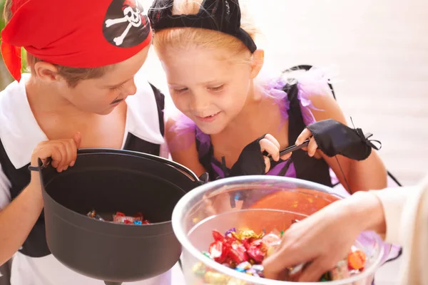 おやつでいっぱいのバケツ 兄と妹はハロウィンに近所の人からお菓子をもらって — ストック写真