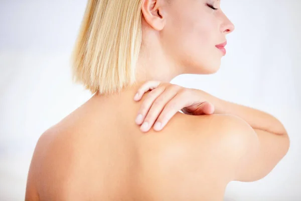 Feeling beautiful. Young woman touching her shoulder against a white background